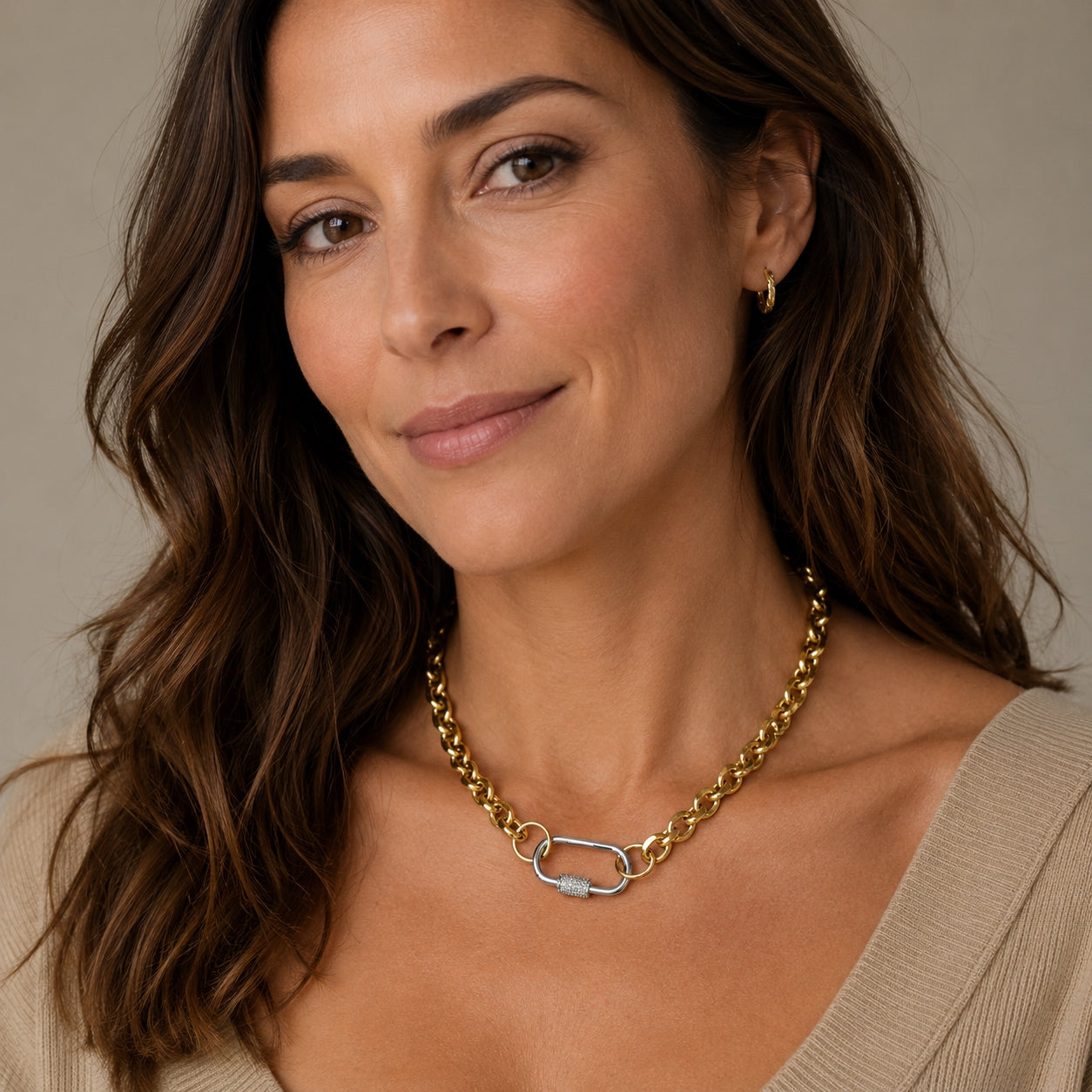 Woman wearing a gold chain necklace with a silver carabiner clasp