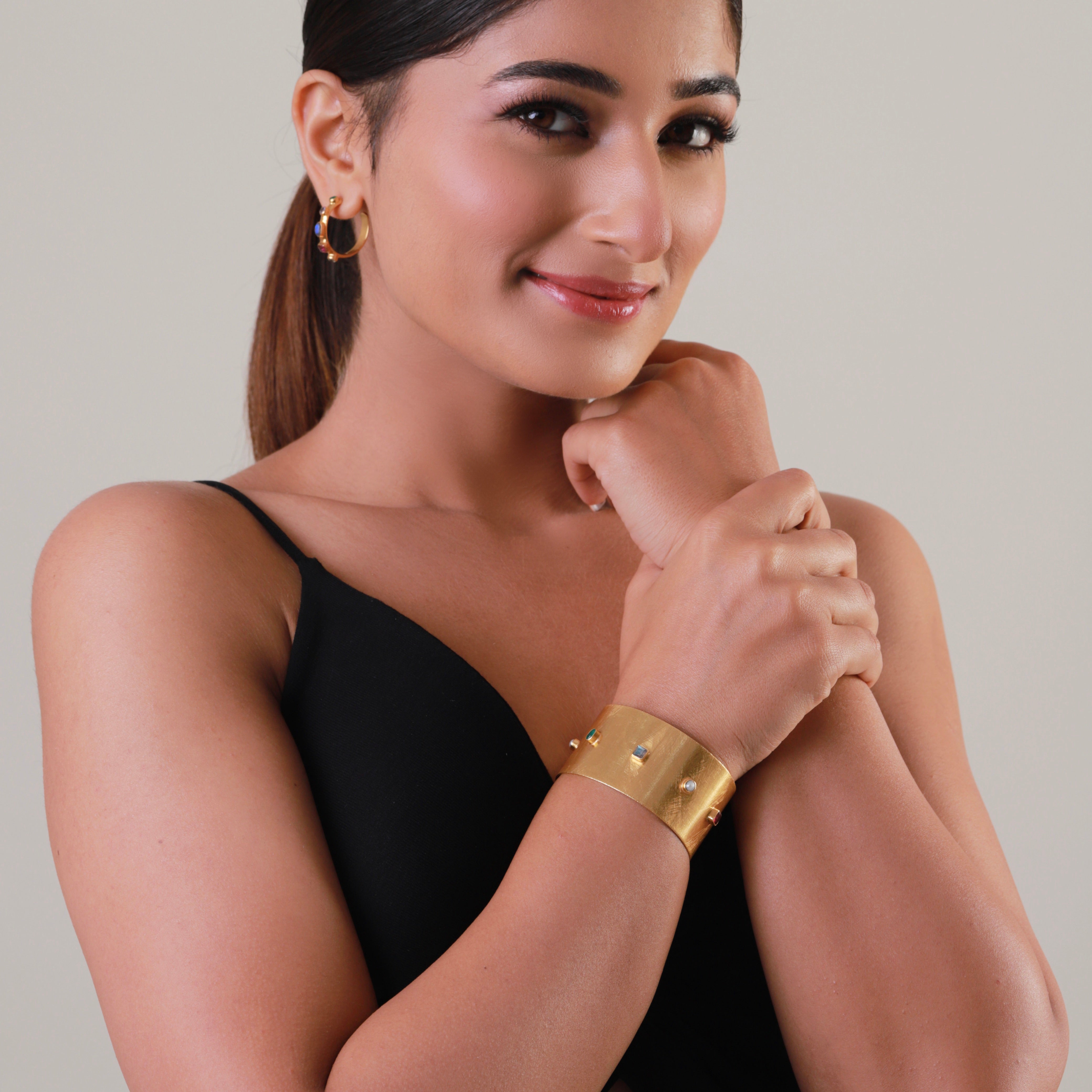 Woman wearing a gold bracelet on a neutral background