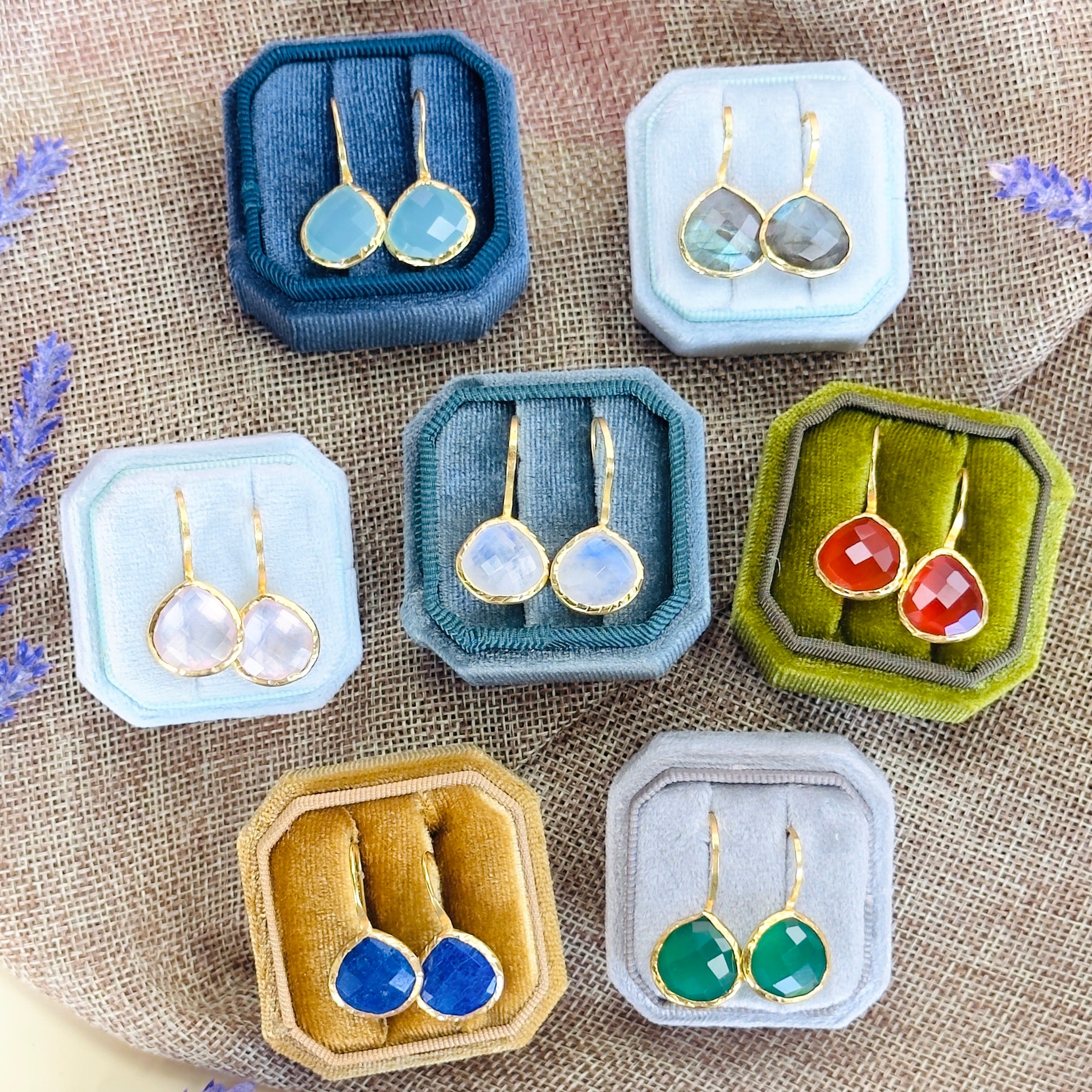 Assorted gemstone drop earrings displayed in coloured velvet jewellery boxes