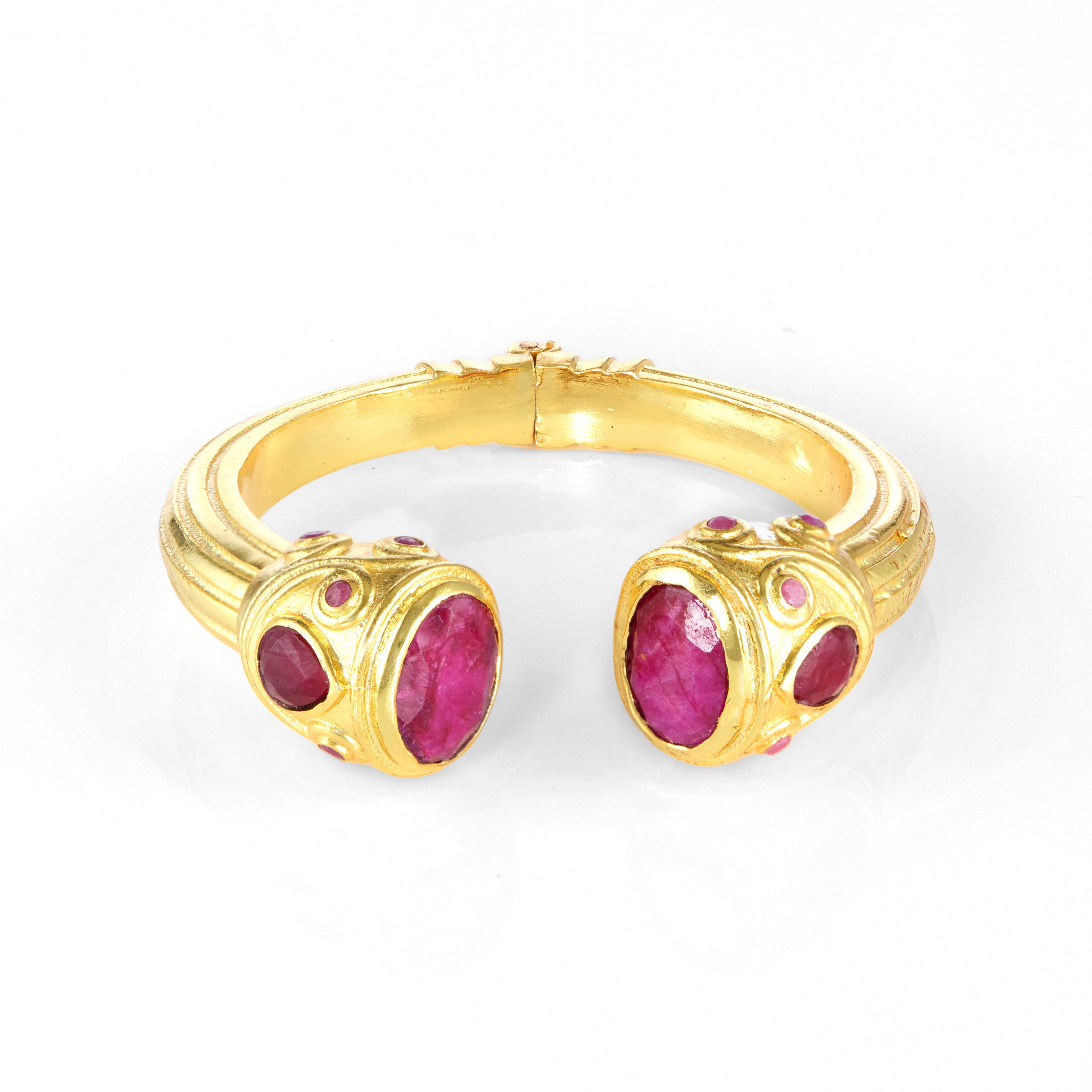 Gold cuff bracelet with oval pink gemstones and decorative detailing