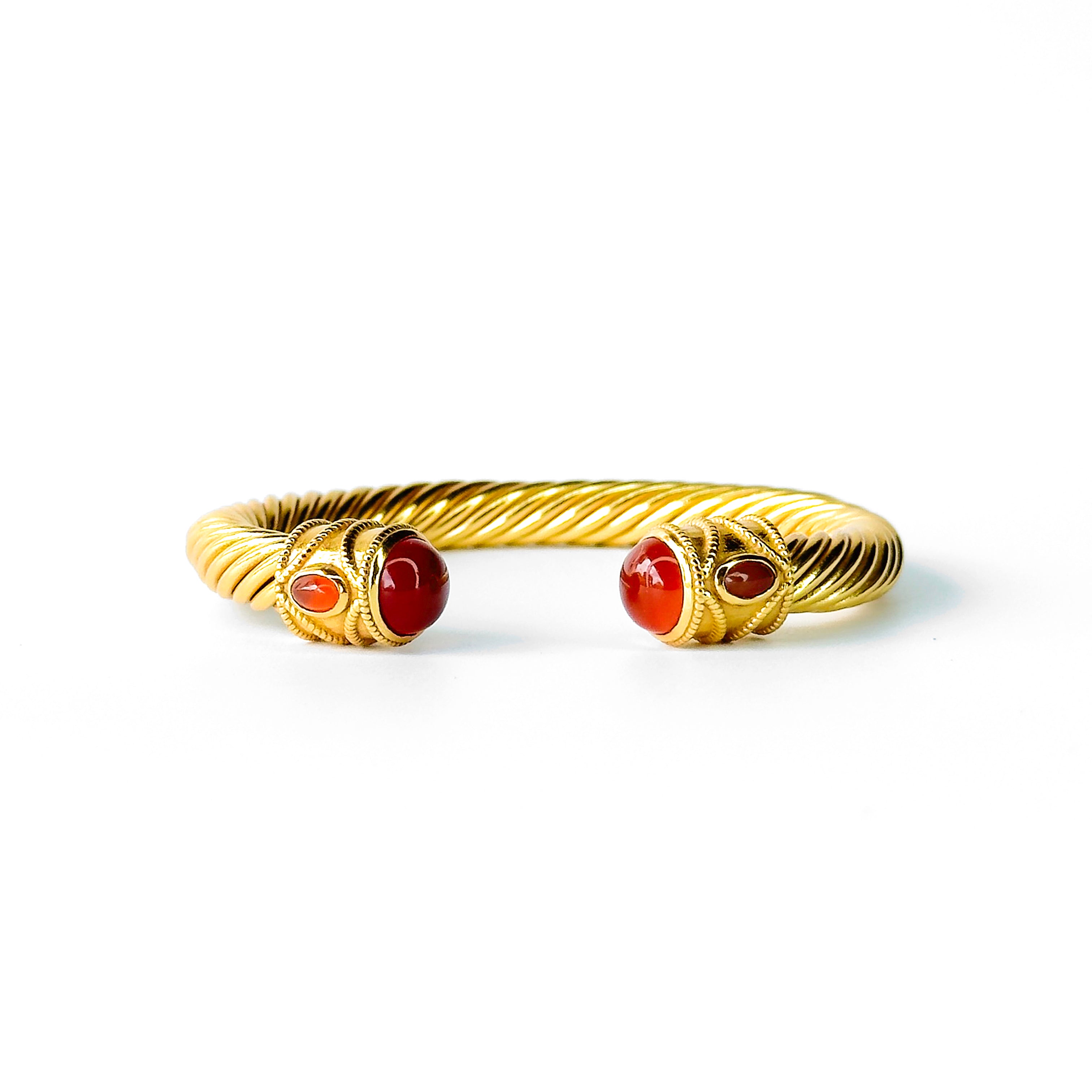 Twisted gold cuff bracelet with red gemstone end stones