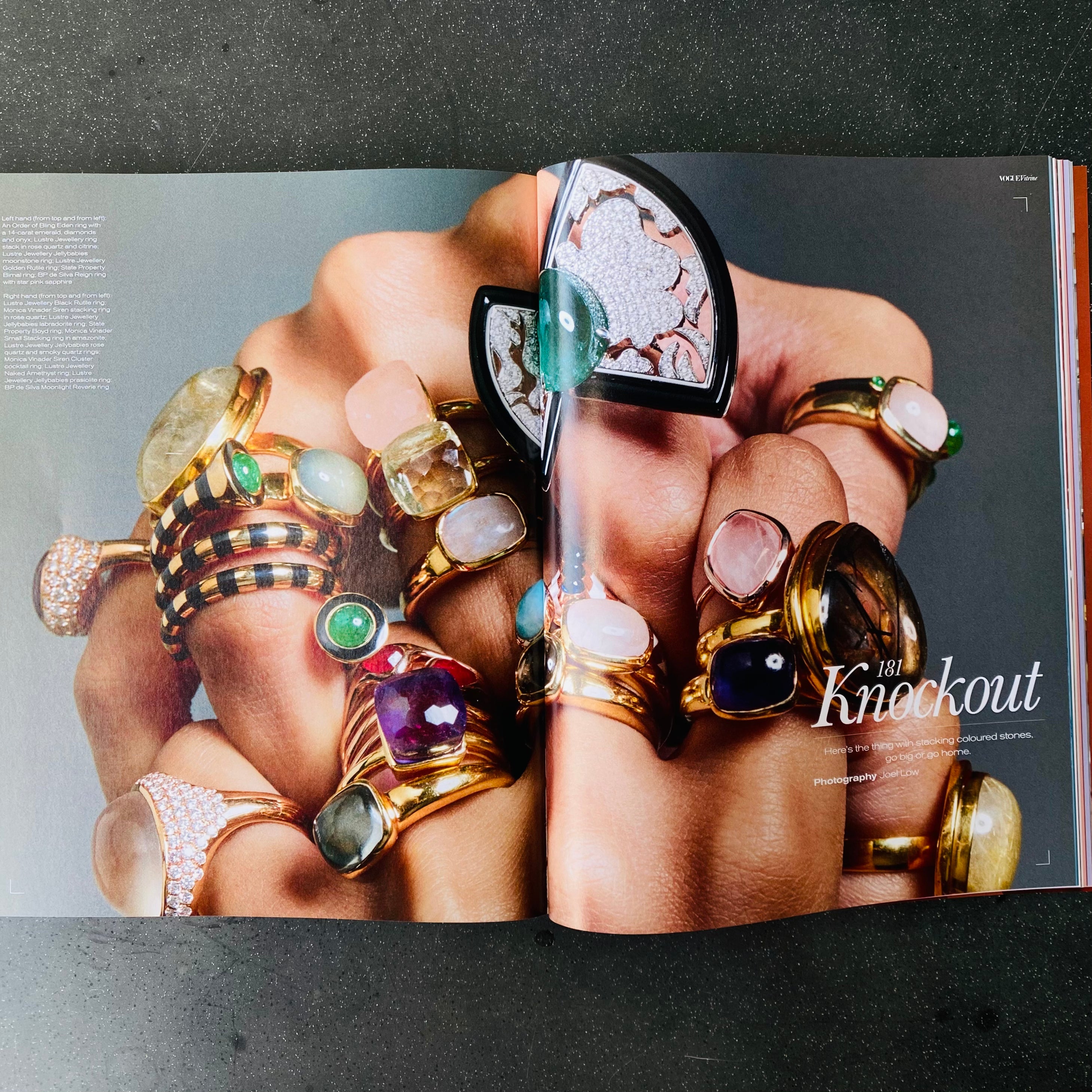 Close-up of hands wearing multiple colourful gemstone gold rings in a jewellery editorial spread